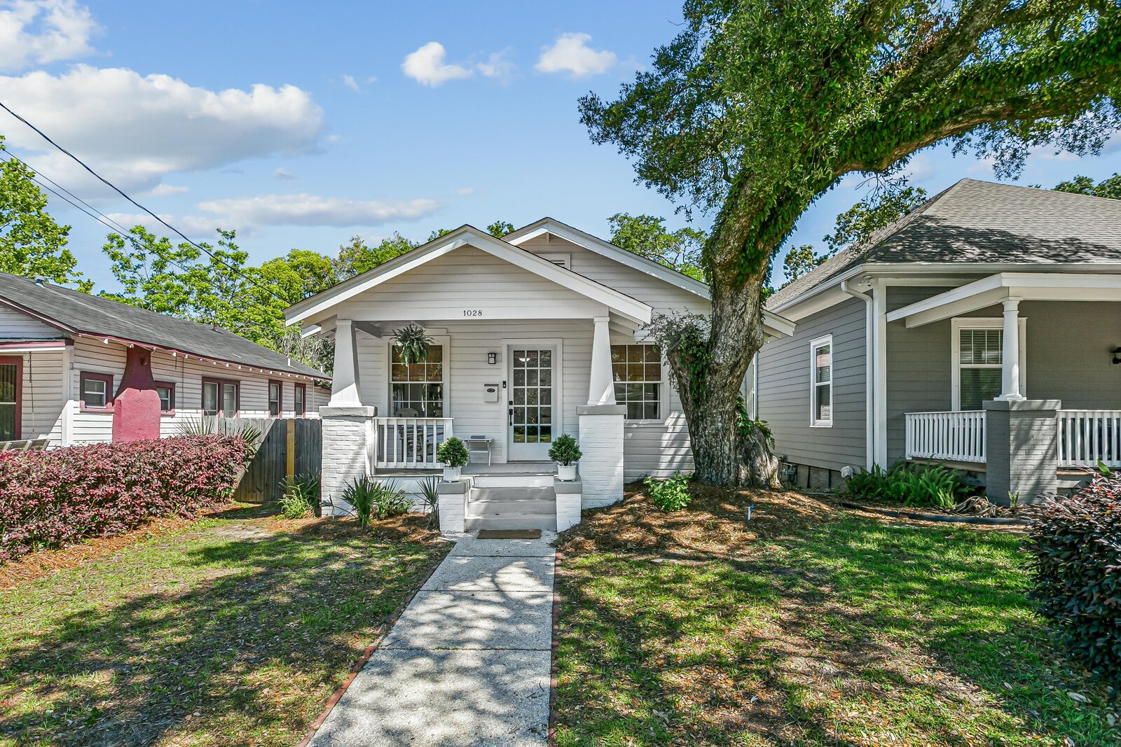 Front exterior of Candy's Cottage with classic craftsman porch and stately oak