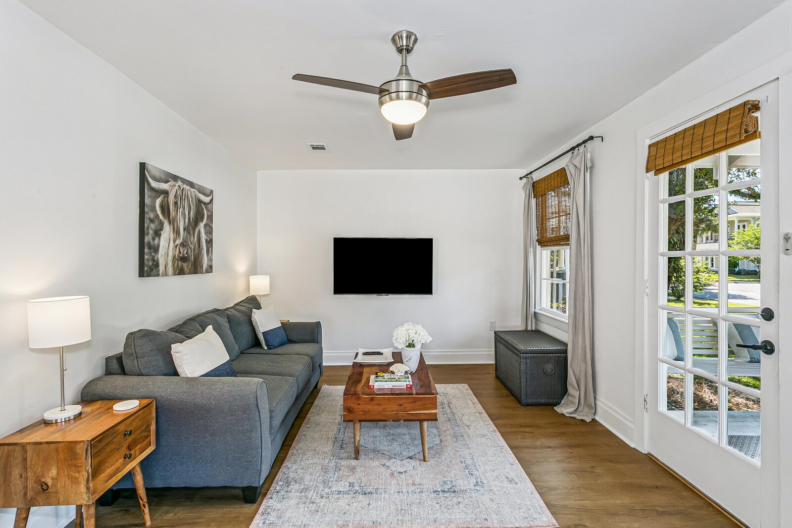 Living room with sofa, TV, ceiling fan, and natural light